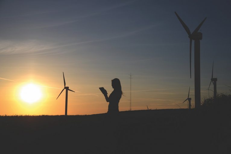 silhouette-of-woman-holding-book-near-windmills-636335